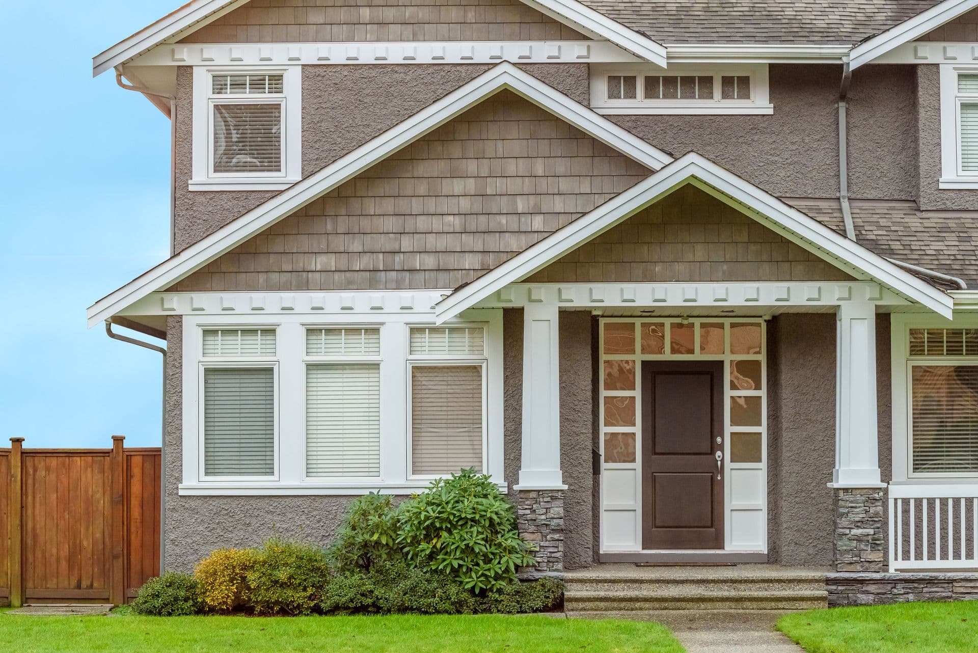 The front of a light brown house with front yard.