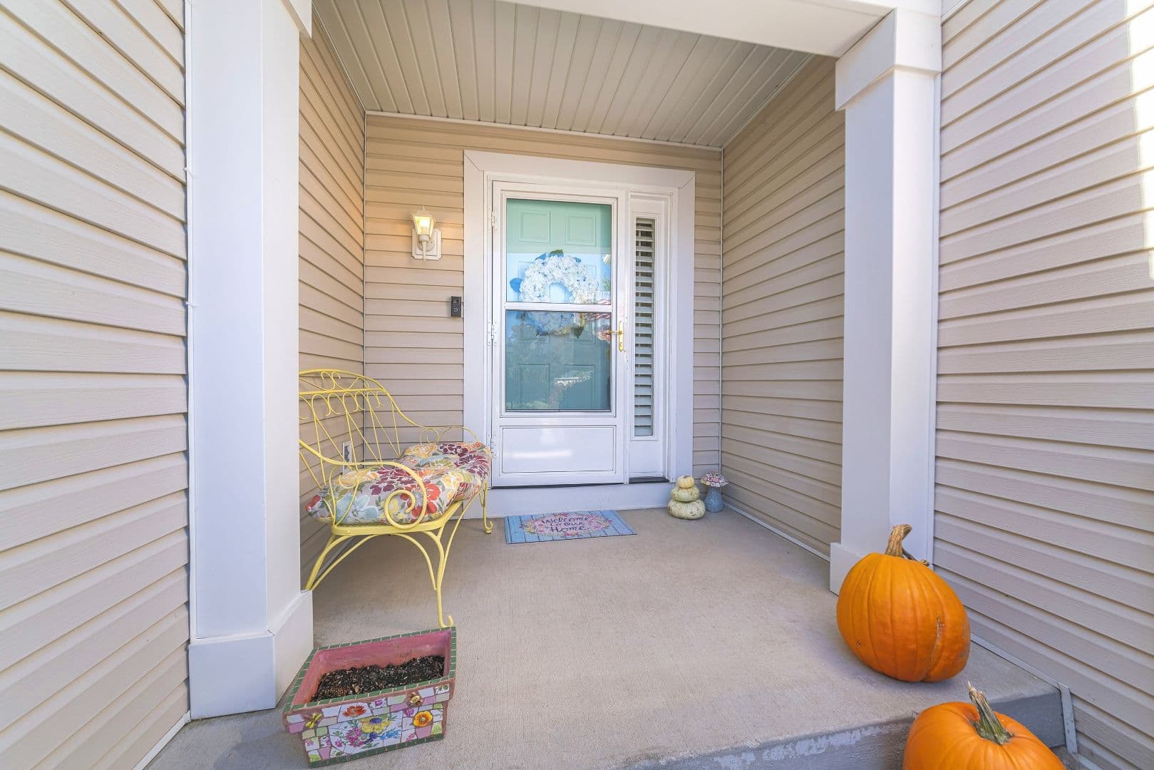 A light tan home with a white front entry door and storm door.