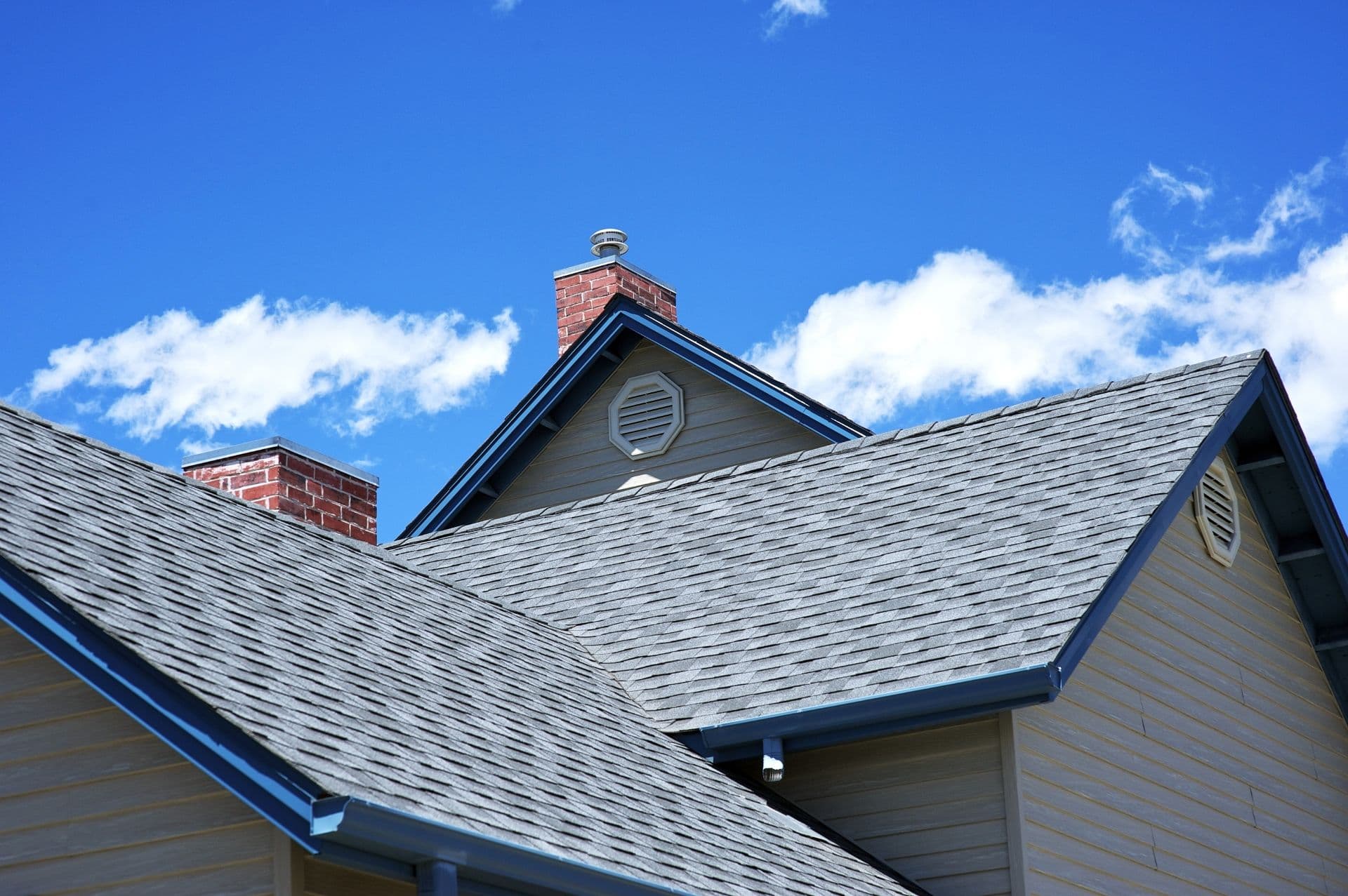 A gray roof with blue gutters and trim on a gray house.