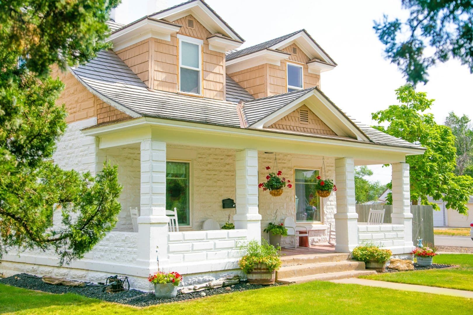 A house with a large, white brick front porch, natural colored siding, and new windows.