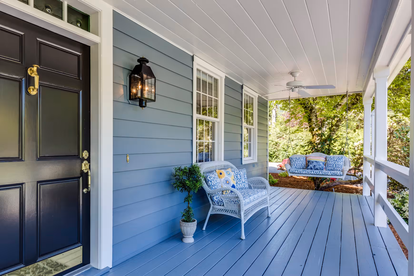 The front porch of a house with blue siding.