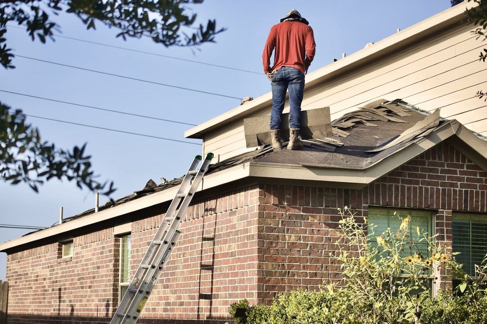A worker removes old roofing shingles.