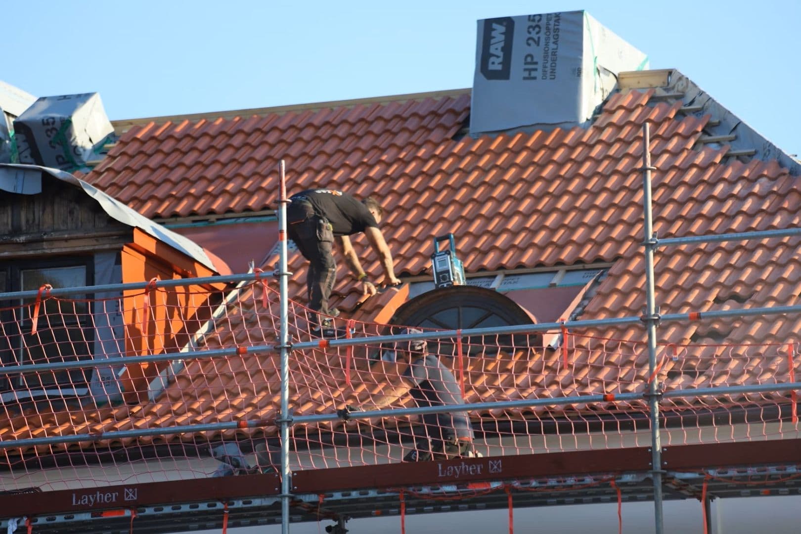 Workers install new tile roofing.